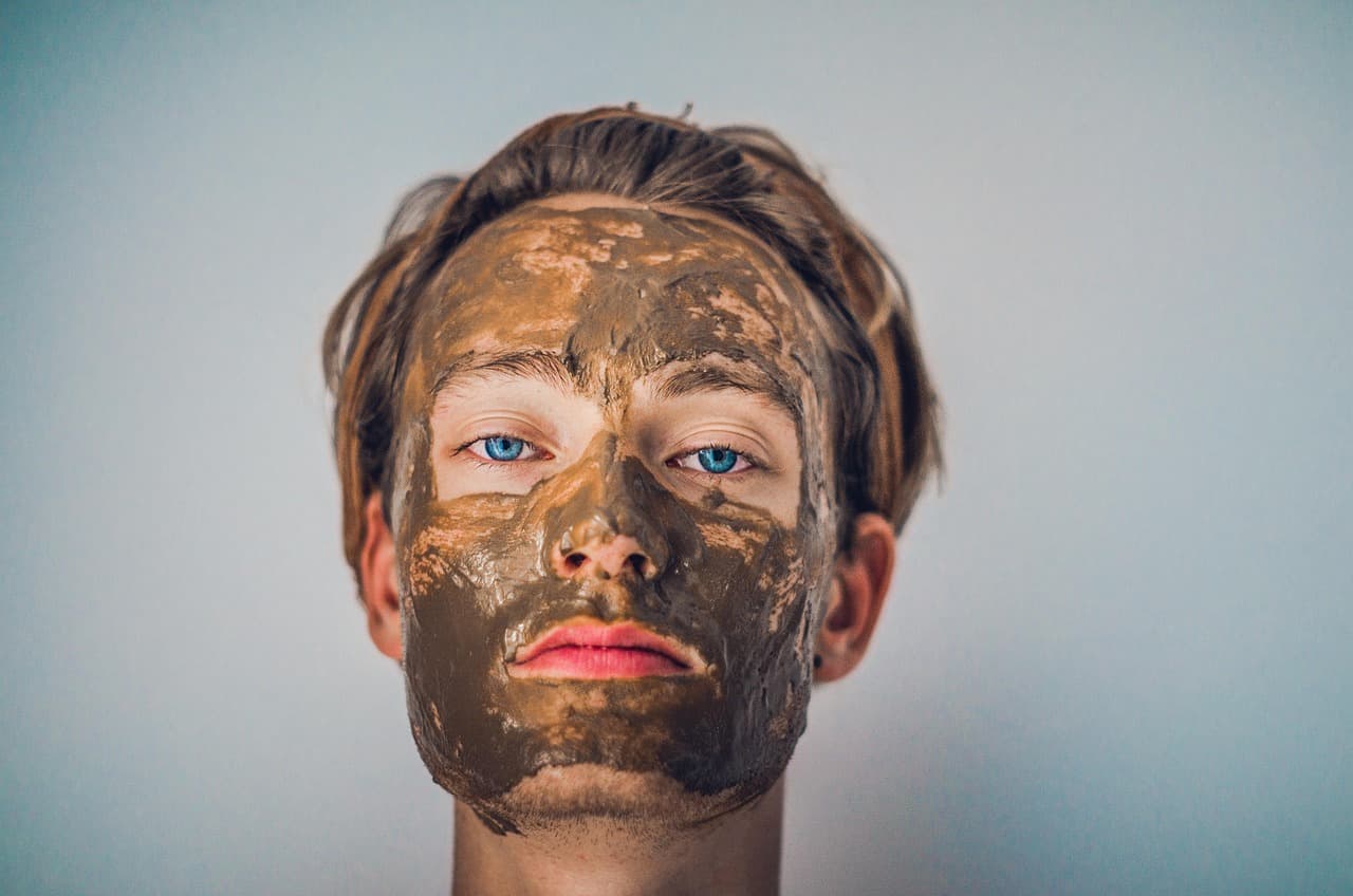 A man wearing a clay face mask
