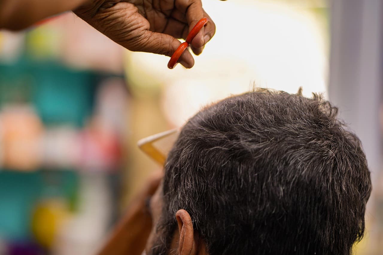 Barber taking comb and scissors to a customer’s dark hair