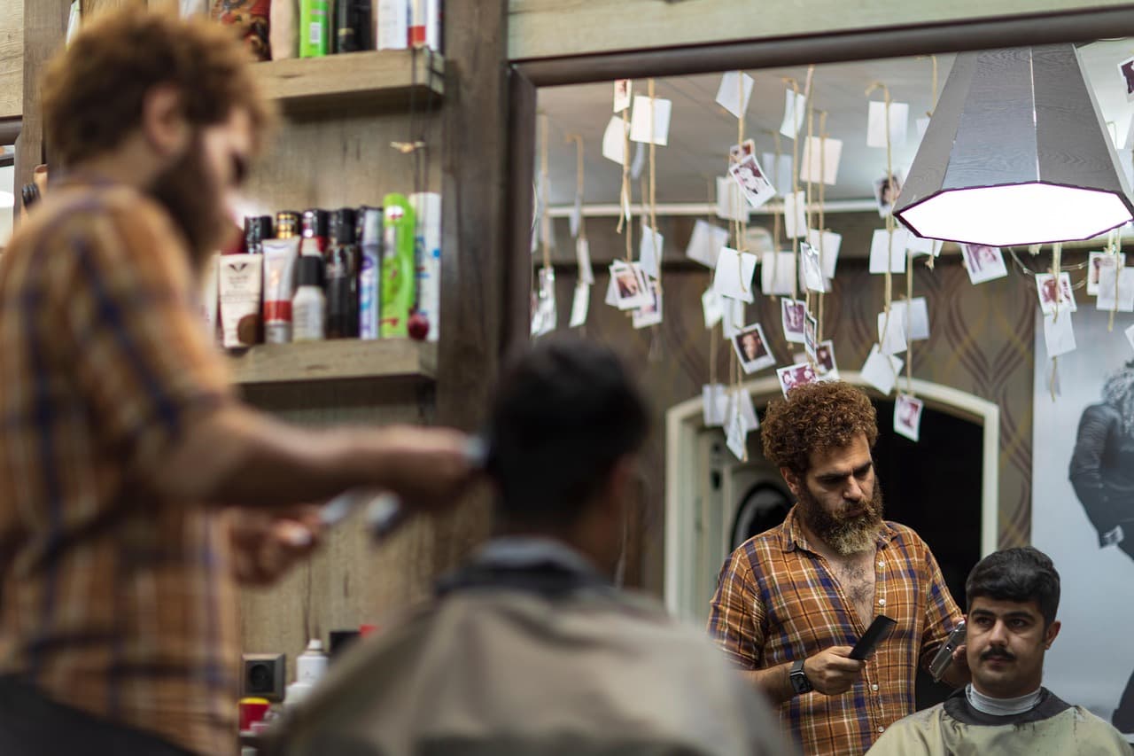 Two barbers cutting side by side in front of the mirrors