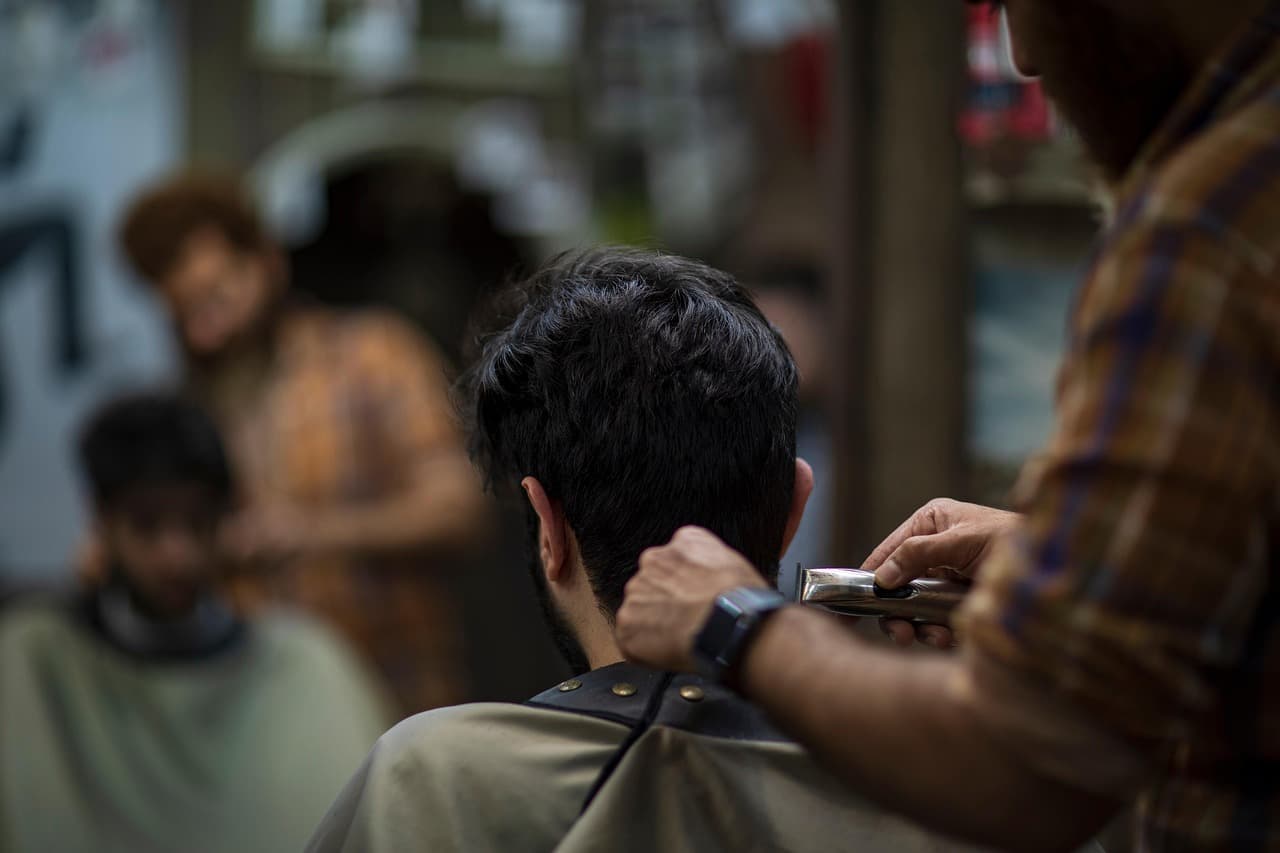 Barber running the clippers up the back of a customer’s neck